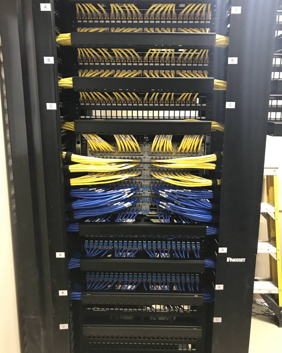 Network rack with neatly dressed yellow and blue patch cables and labeled patch panels